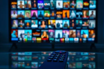 A sleek remote on a glass table before a vibrant grid of streaming thumbnails.